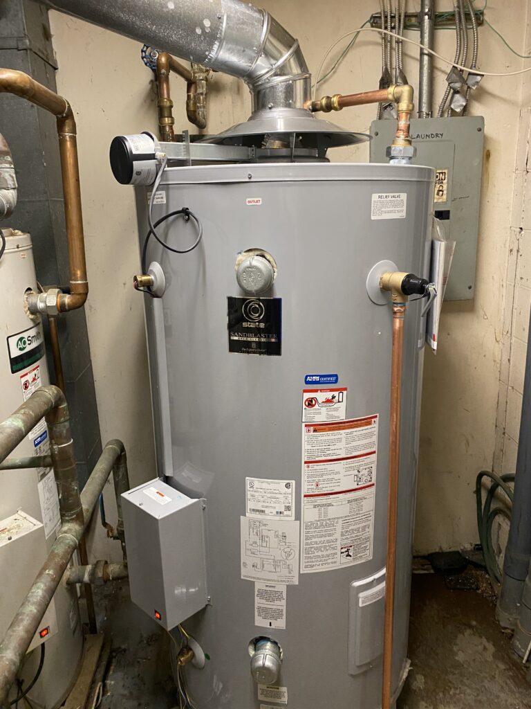 Large commercial gas water heater next to an older tank in a South St. Louis County utility room, on a Liberty service call