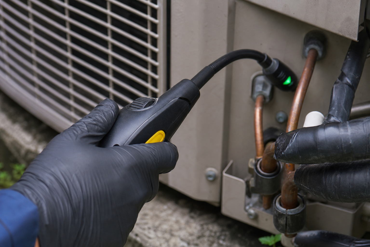 Close shot of an HVAC technician's gloved hands holding an electronic refrigerant leak detector probe