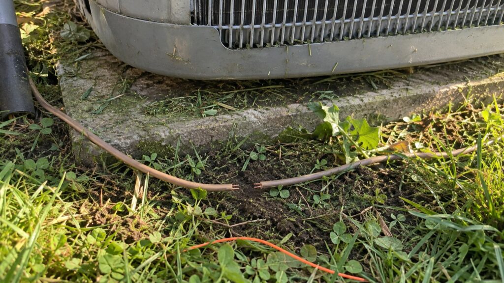 Cut thermostat wire in the grass at the base of an outdoor AC unit after string trimming