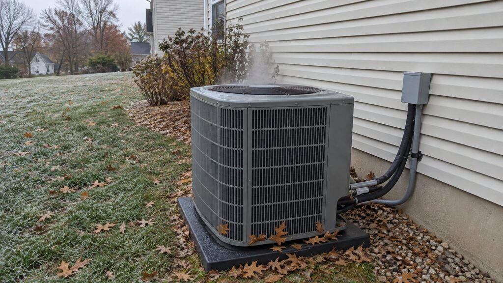 Heat pump outside a house near St. Louis on a frosty late October morning with leaves against the unit
